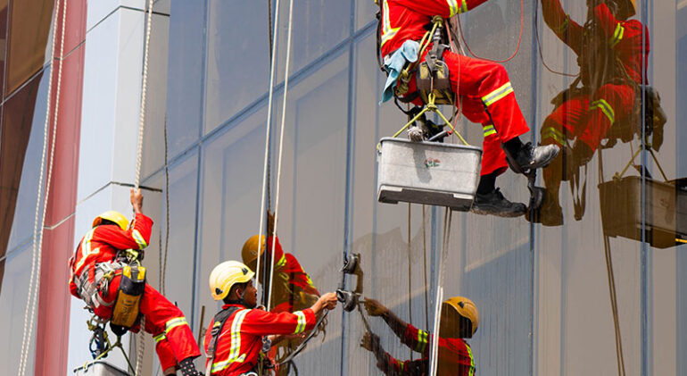 Technician cleaning a high-rise glass facade in Dubai – glass facade maintenance