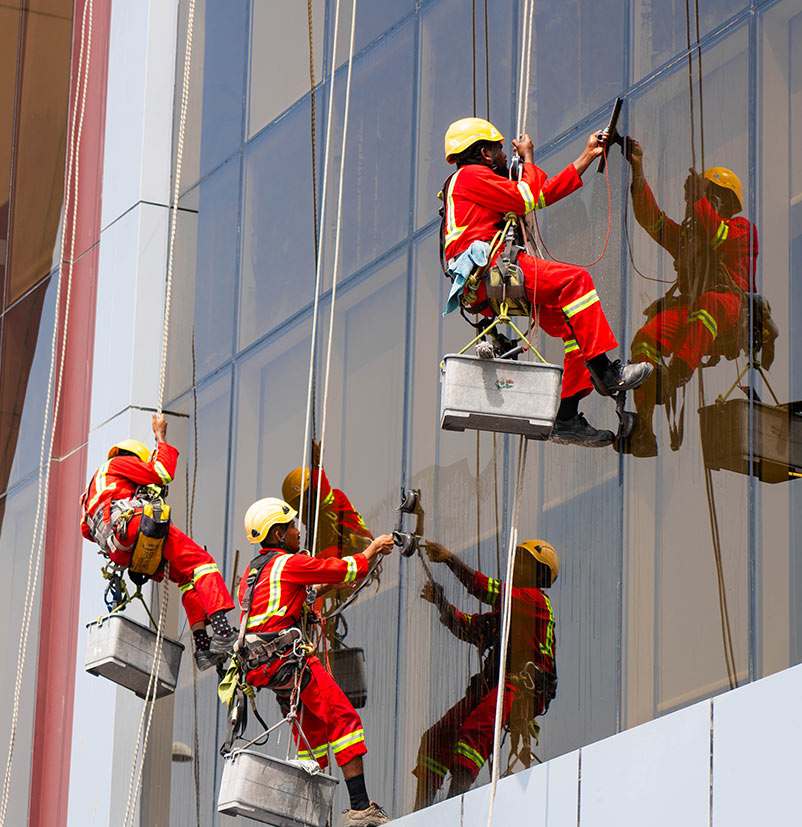 Technician cleaning a high-rise glass facade in Dubai – glass facade maintenance